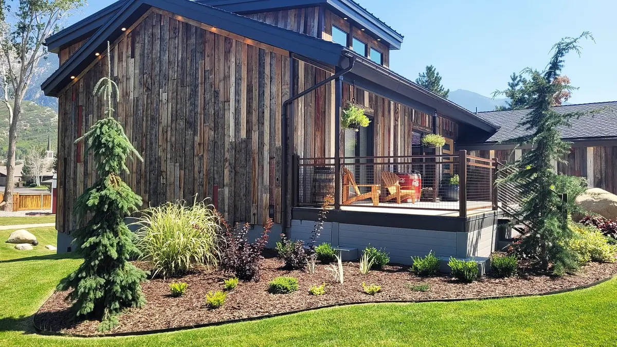 Evergreens and grasses beside a timber-clad porch