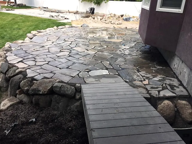 Flagstone patio with a boulder edge and wood bridge