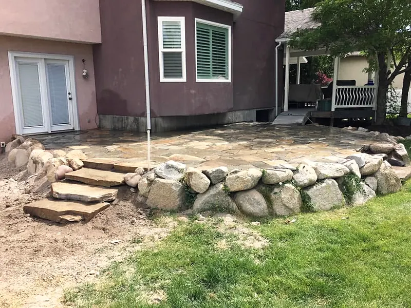 Flagstone patio with a boulder wall and steps