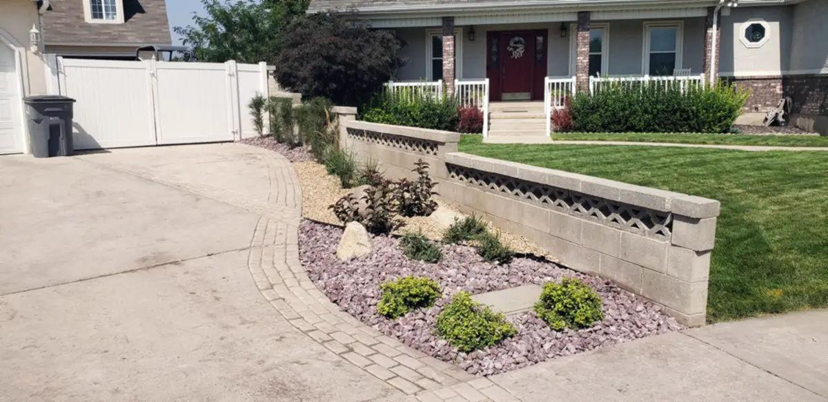 Rock bed with shrubs beside a block wall